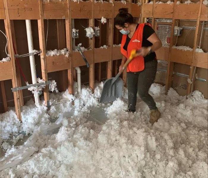 woman cleaning up insulation debris 