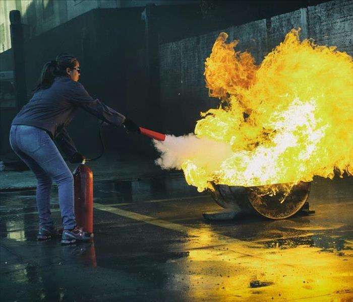 Lady using fire extinguisher to put out fire. 